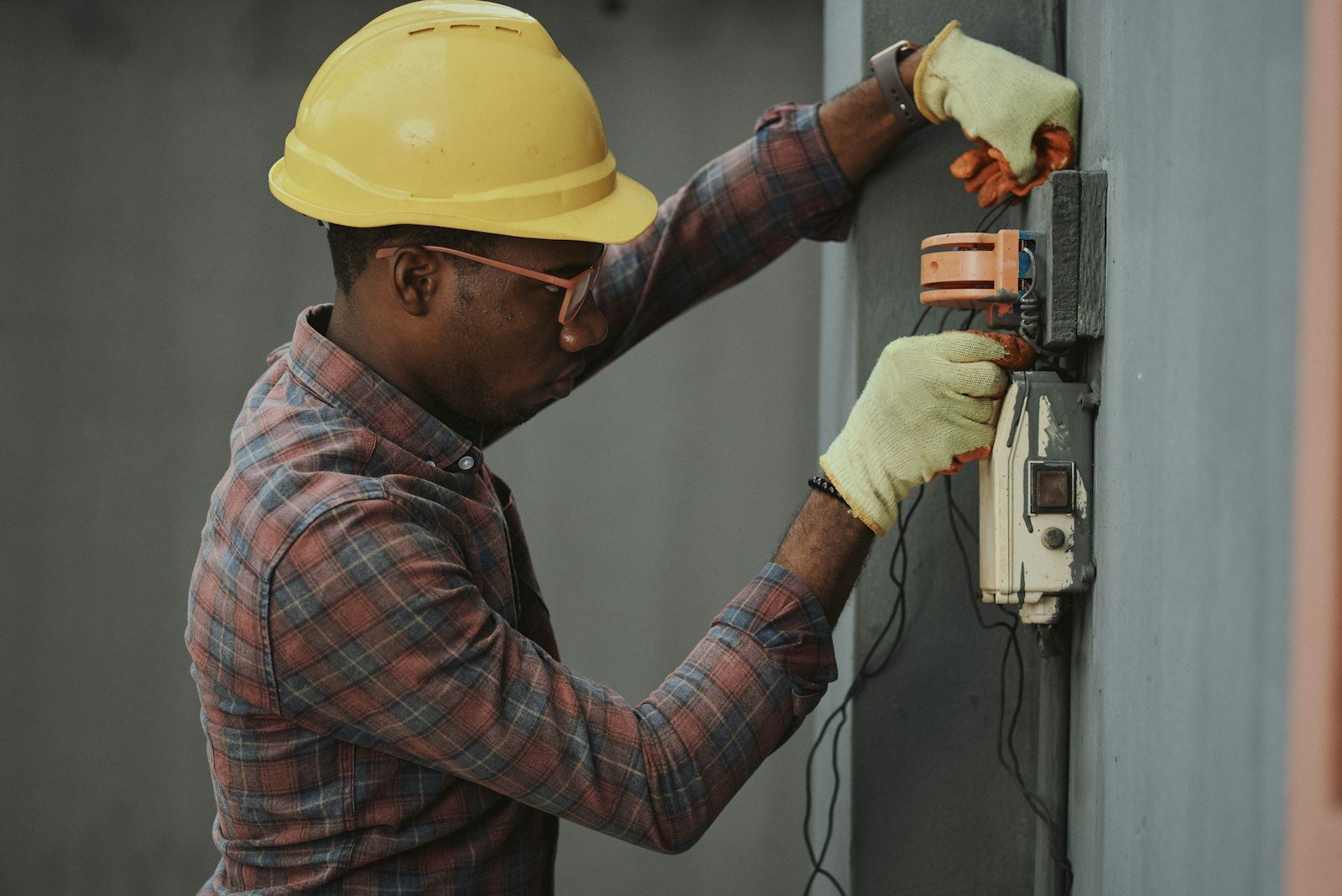 Young African technician in safety gear installing electrical equipment